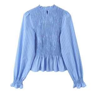 Détail d'une blouse à rayures bleues avec plastron smocké et finitions à col volanté
