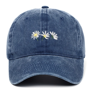 Dettaglio ricamo margherita bianca su berretto da baseball in denim blu lavato