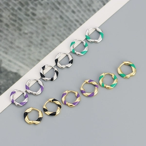 Detail view of colorful enamel twisted huggie hoop earrings in gold and silver finish