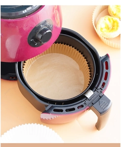 Detail of round brown parchment paper liner placed inside a red and black air fryer basket