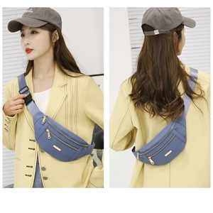 Blue nylon crossbody waist bag with multi-zipper layers and adjustable strap shown on model