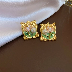 Detailed macro view of square gold earring with pink enamel rose and pearl detail