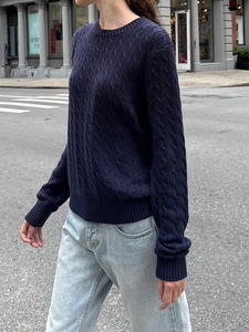 Detailed close-up of dark blue cable knit texture on a long-sleeve casual crewneck sweater
