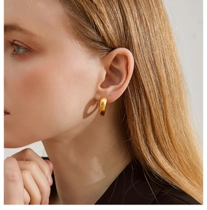 Close-up of a model wearing a minimalist golden teardrop earring with high polished finish
