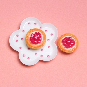Close-up of miniature red fruit tarts and flower plate for dollhouse DIY decoration
