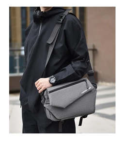 Detail view of a gray messenger bag with adjustable black strap and FASHION BAG text
