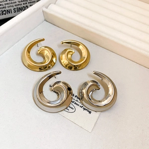Close-up of gold and silver spiral snail stud earrings on a white jewelry display tray