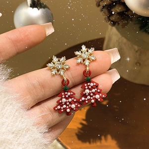 Detail of Christmas tree earrings with snowflake studs and pearls on a festive background