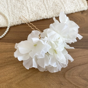 Detailed view of white fabric floral hair pin with elegant gold U-shaped metal fork