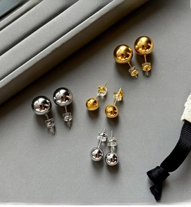 Detailed view of spherical stud earrings in gold and silver with various sizes