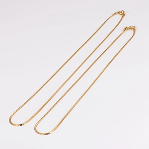 Macro shot of two 2mm golden flat snake chain necklaces on white background