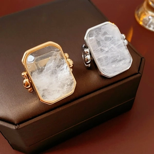 Dettaglio di anelli con pietra quadrata e texture a crepe in finitura oro e argento