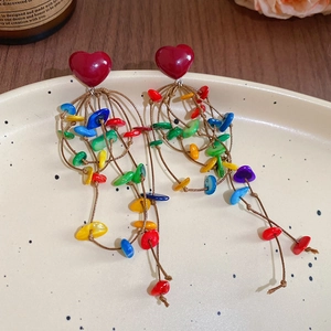 Macro detail of colorful tassel earrings with red heart base and acrylic shell beads