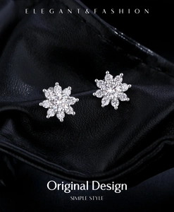 Detailed macro view of snowflake silver stud earrings on a premium black leather texture
