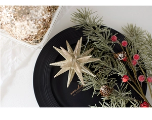 Golden glitter star Christmas ornament with pine needles and berries on a decorative tray