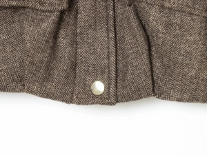 Detailed macro view of brown herringbone wool fabric with a gold decorative button