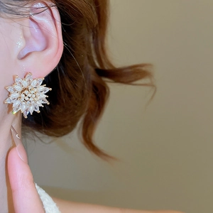 Detailed close-up of sun flower stud earring with marquise pearls and zircon on model ear