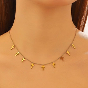 Close-up of a gold necklace with nine small cross charms worn by a female model