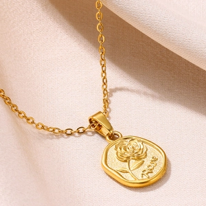 Gros plan détaillé du pendentif rose en acier plaqué or 18k sur satin beige