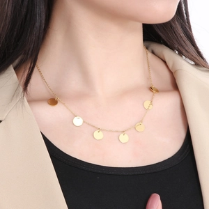 Close-up of golden stainless steel necklace with round disc pendants on a female model