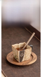 Detail of vintage ceramic espresso cup with daisy motif, gold rim and wooden tray