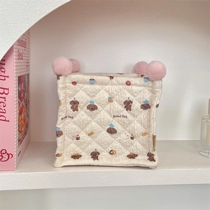 Detailed shot of quilted fabric storage bin with cute bread dog print and pink pom-poms