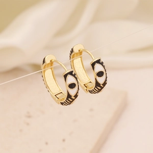 Macro detail of gold-plated evil eye hoop earrings with enamel drip oil finish