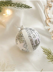 Detail of silver Merry Christmas glitter ball ornament with pine needles and warm lights