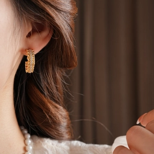 Close-up of a 18k gold plated C-shaped chain earring with crystals on model's ear