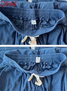 Detail of navy corduroy pants featuring an elastic waist with cream drawstring and labels