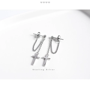 Macro detail of sterling silver cross pendant with chain earring on white background