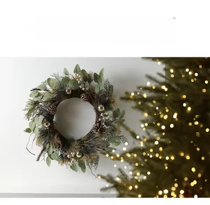 Close-up of a Nordic Christmas wreath with pine cones and gold balls on a white wall