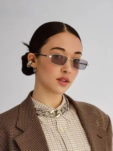 Modelo con gafas de sol cuadradas de metal con lentes lavanda y cadena de plata gruesa