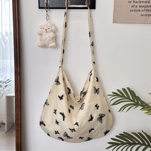 Close-up of cream butterfly print lace tote bag with natural fabric texture on hook