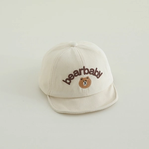 Gros plan d'une casquette beige pour bébé avec broderie ours et texte bearbaby