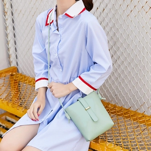 Minimalist mint green leather bucket bag with thin shoulder strap and metal buckle