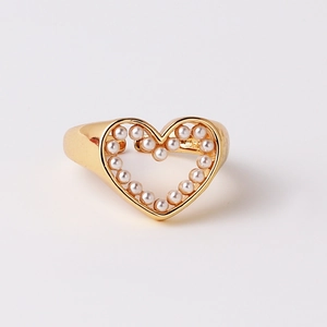 Detail of gold hollow heart ring with inlaid white pearls on a clean white background