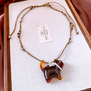 Detail view of resin cat pendant with pearl collar and floral accent on brown cord