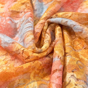 Macro shot of colorful floral lace fabric detail with vibrant orange and pink mesh texture