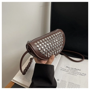 Detail of brown lychee leather crescent bag featuring silver studs and woven strap