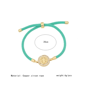 Macro detail of turquoise rope bracelet with gold copper and zircon religious medal