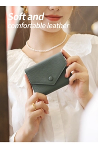 Close-up of pebble-textured leather envelope wallet in deep teal with snap button closure