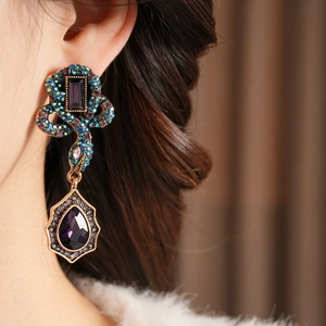 Gros plan de boucles d'oreilles serpent vintage avec pierres violettes sur le modèle