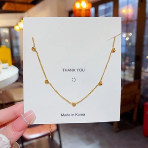 Close-up of a delicate gold heart tassel necklace on a display card for women