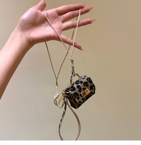 Close-up of leopard print mini bag pendant with gold lock and woven lanyard detail