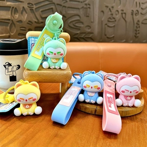 Adorables porte-clés chat floqués aux couleurs pastel sur une mini chaise en bois au café