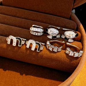 Detail of silver M-letter ear clips and zircon snake earrings in a velvet jewelry box