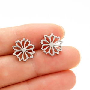 Gros plan détaillé de petites boucles d'oreilles fleurs argentées sur un doigt