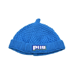 Detailed close-up of sky blue knitted baby beanie with a white Plig logo patch