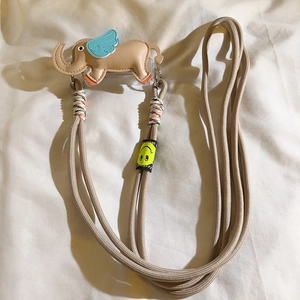 Detail of beige woven nylon phone lanyard featuring a cute elephant charm with blue wings